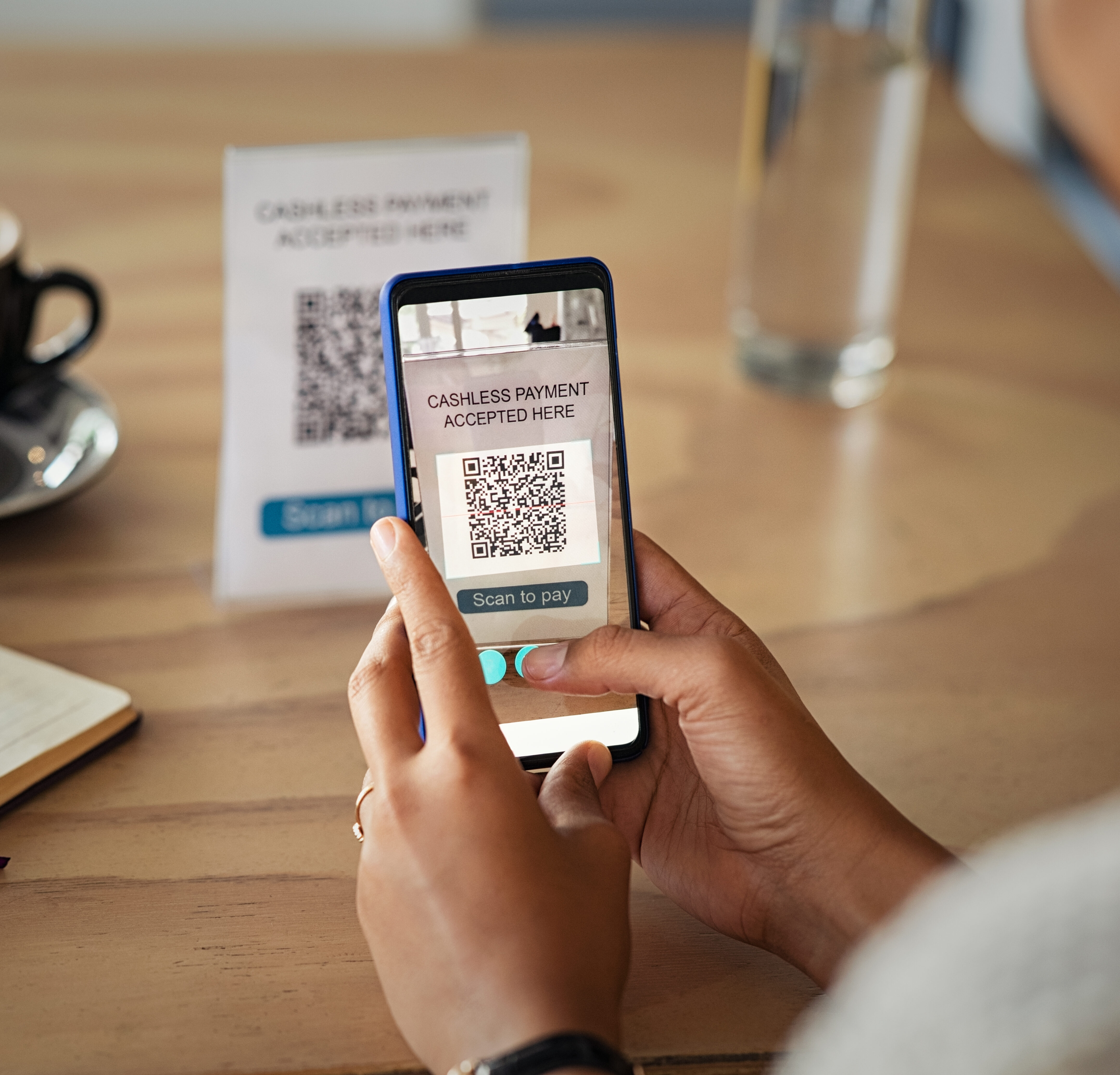 Woman scanning barcode with phone to pay at cafeteria